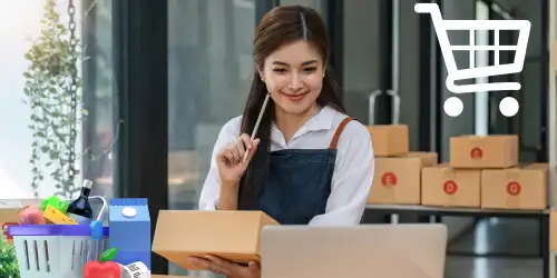 A person is working on a laptop while holding a shopping cart